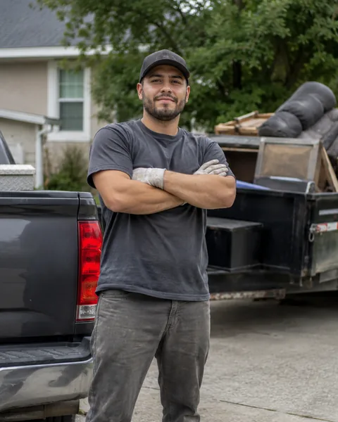 Junk removal owner beside a loaded dump trailer